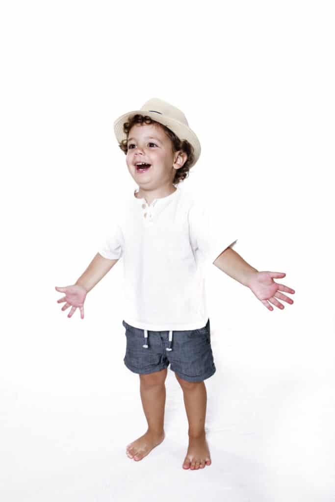 Niño con gorro con los brazos abiertos ríe en sesión infantil