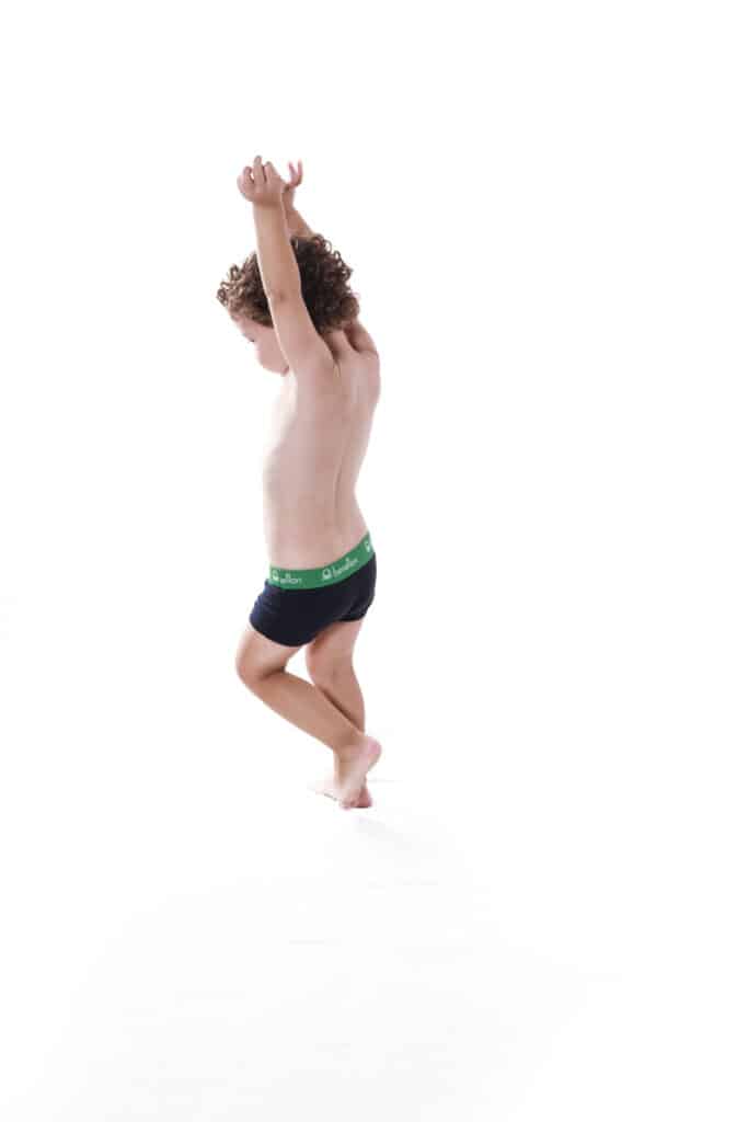 niño en bañador juega durante sesión de fotos infantil