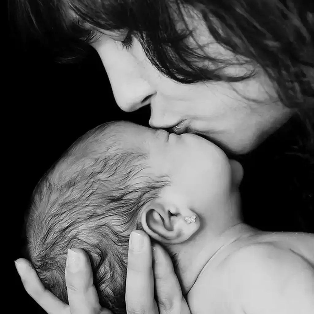 Madre besando a su recién nacido en una sesión fotográfica newborn