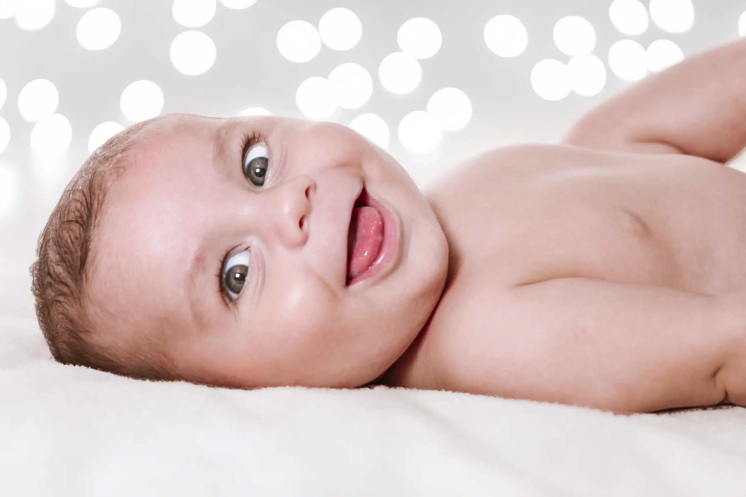 Bebé sonriente con fondo de luces blancas navideñas