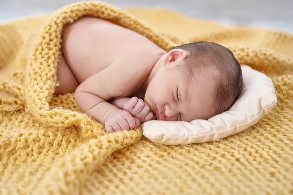 Recién nacido dormido con manta amarilla