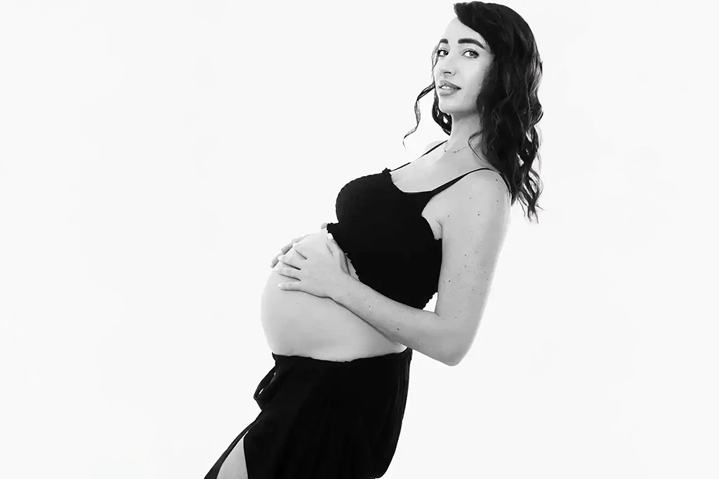 Sesión de embarazo sola en blanco y negro, con fondo claro en estudio